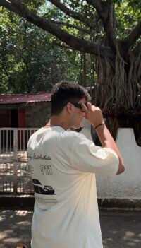 A clean cream oversized tee featuring a bold Porsche 911 graphic on the back — minimal in the front, streetwear statement at the back