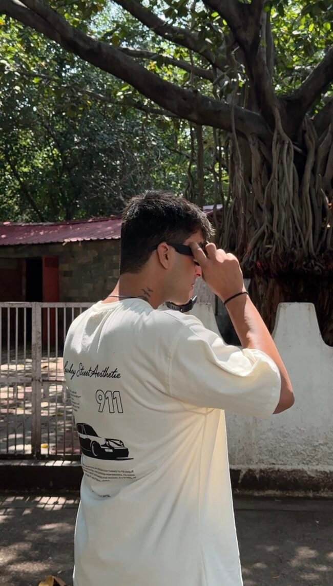 A clean cream oversized tee featuring a bold Porsche 911 graphic on the back — minimal in the front, streetwear statement at the back