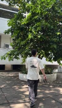 A clean cream oversized tee featuring a bold Porsche 911 graphic on the back — minimal in the front, streetwear statement at the back