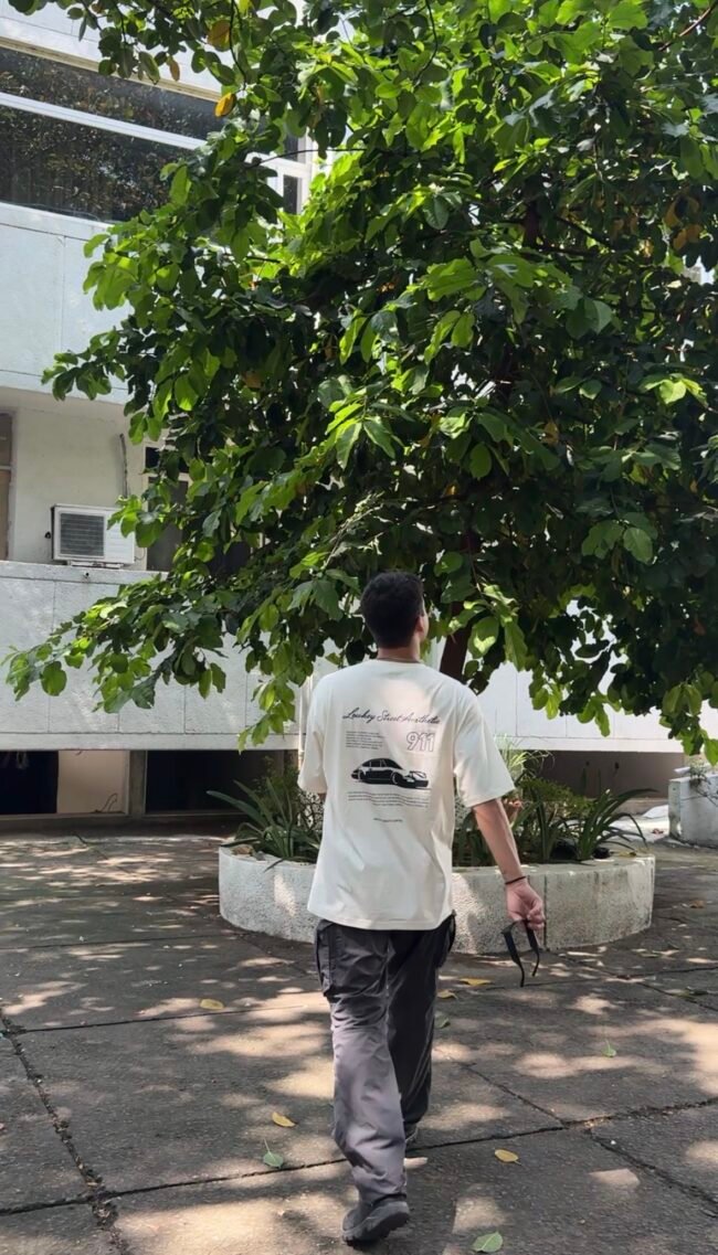 A clean cream oversized tee featuring a bold Porsche 911 graphic on the back — minimal in the front, streetwear statement at the back